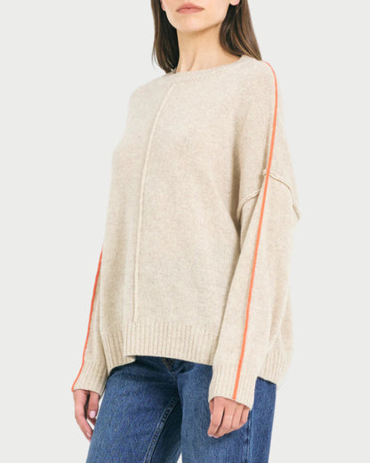 Woman wearing a beige sweater with orange accents on a white background