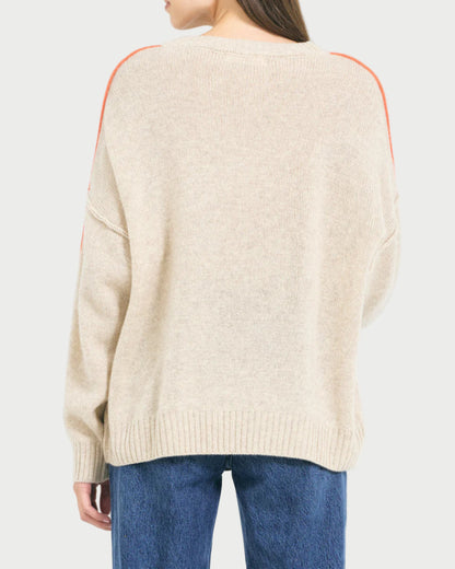 Woman wearing a beige sweater with orange accents on a white background