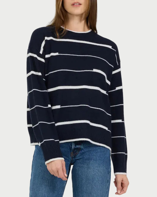 Woman wearing a navy and white striped sweater and blue jeans on a white background