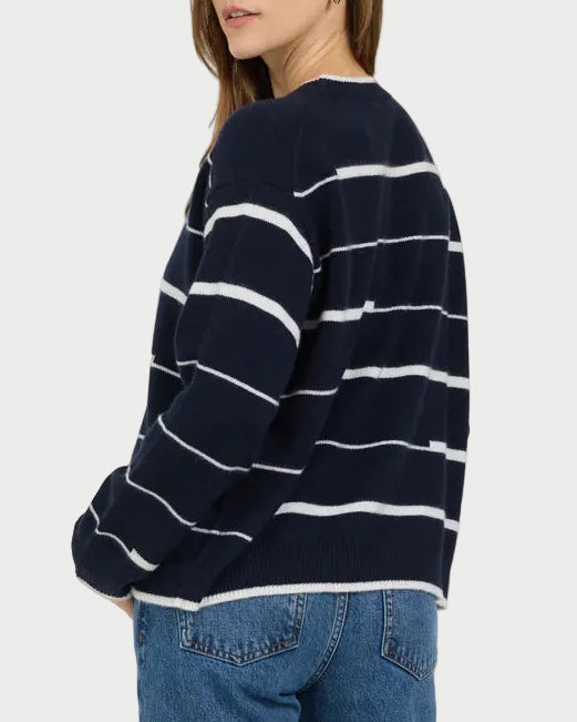 Person wearing a navy and white striped sweater and blue jeans on a light gray background