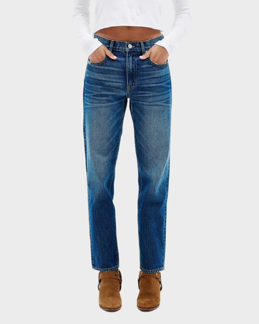 Woman wearing a white long-sleeve top and blue jeans on a white background