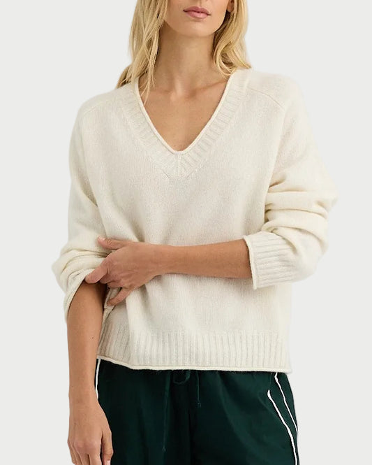 Person wearing a white sweater and green pants with white stripes on a white background