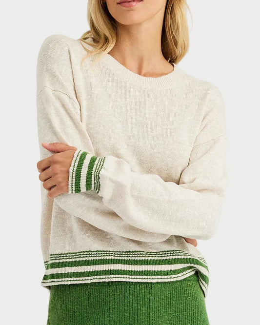 Woman wearing a white sweater with green accents and a green skirt on a white background