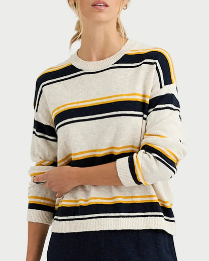 A woman wears the One Grey Day Susannah Pullover, a lightweight knit sweater by One Grey Day with black and yellow stripes, long sleeves, and a classic round neckline. She stands with one arm bent; her face is partially out of frame.