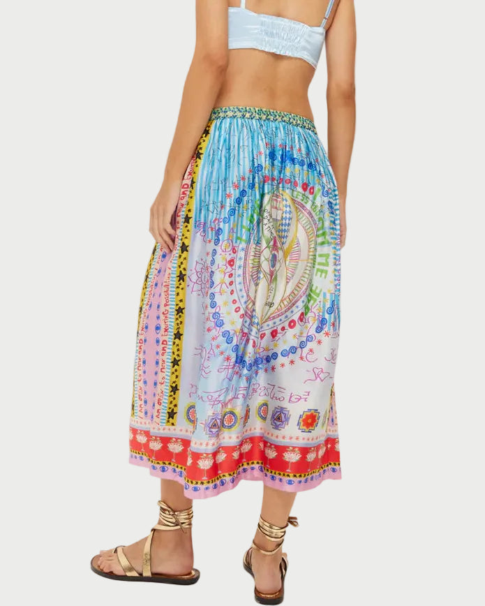 Woman wearing a colorful patterned skirt and light blue top on a white background