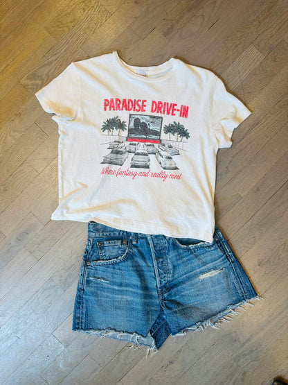 A RE/DONE Drive In Tee and denim cutoff shorts are laid flat on a wooden floor.