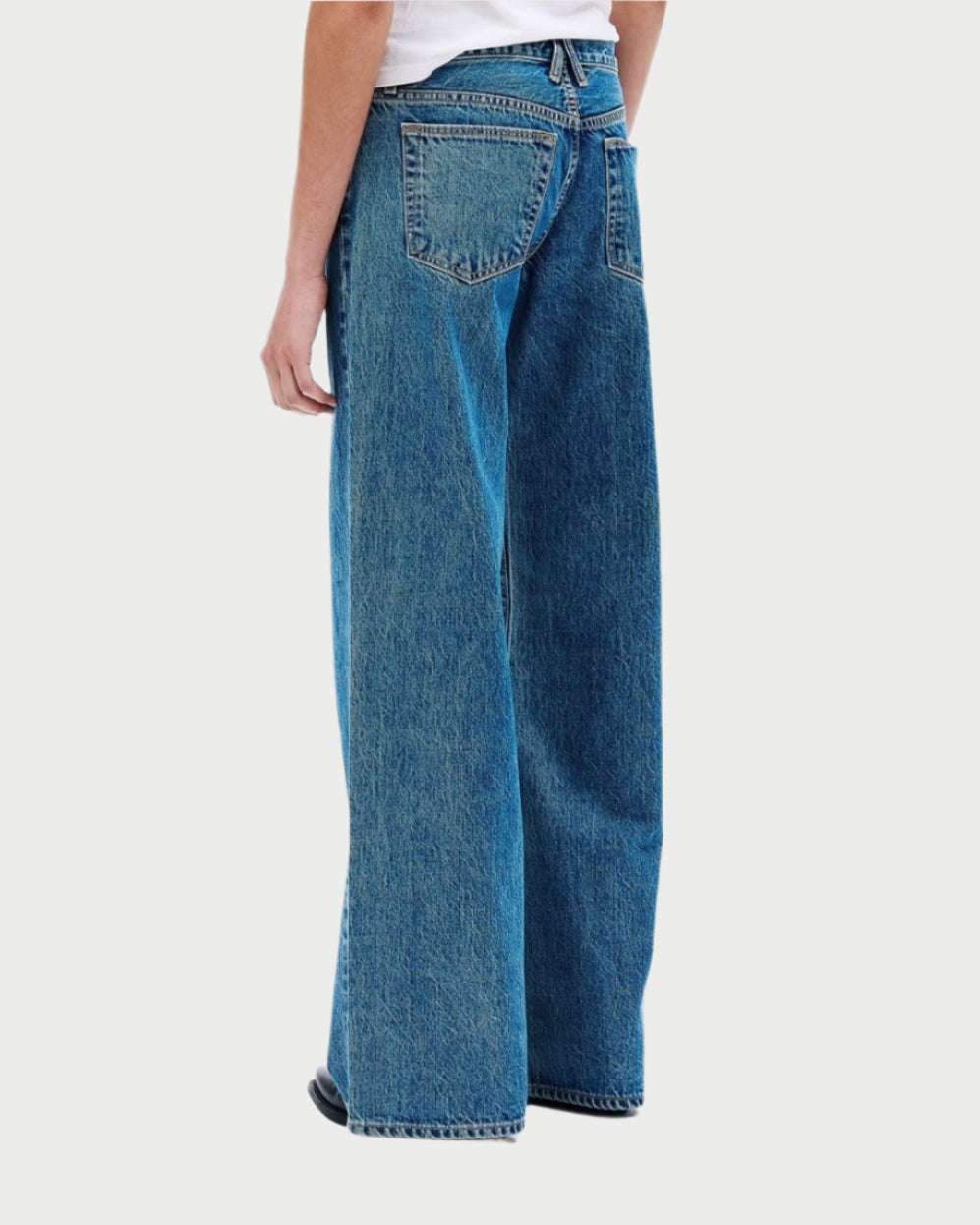 Person wearing blue jeans and a white t-shirt on a white background