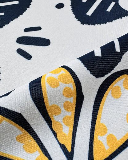 Close-up of a fabric with a pattern of yellow, black, and white shapes.