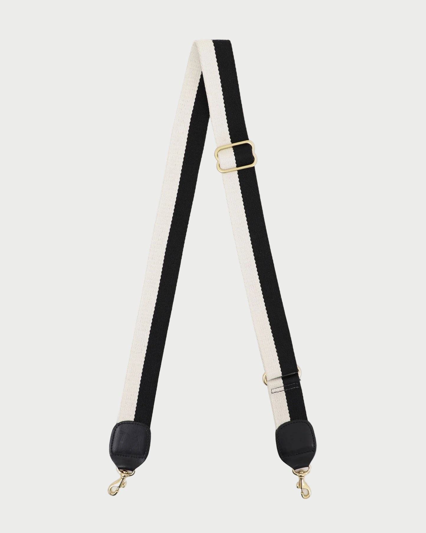Black and white strap with gold hardware on a white background