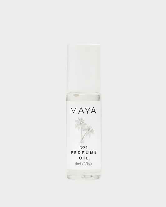 A clear glass bottle of MAYA’s Maya No.1 Mini 5ML Perfume Oil features a white cap, minimalist label, and palm tree graphics, evoking an exotic escape and emphasizing sustainability—all set against a light backdrop.