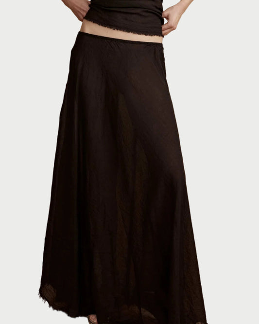 Woman wearing a black sleeveless top and long black skirt against a beige background