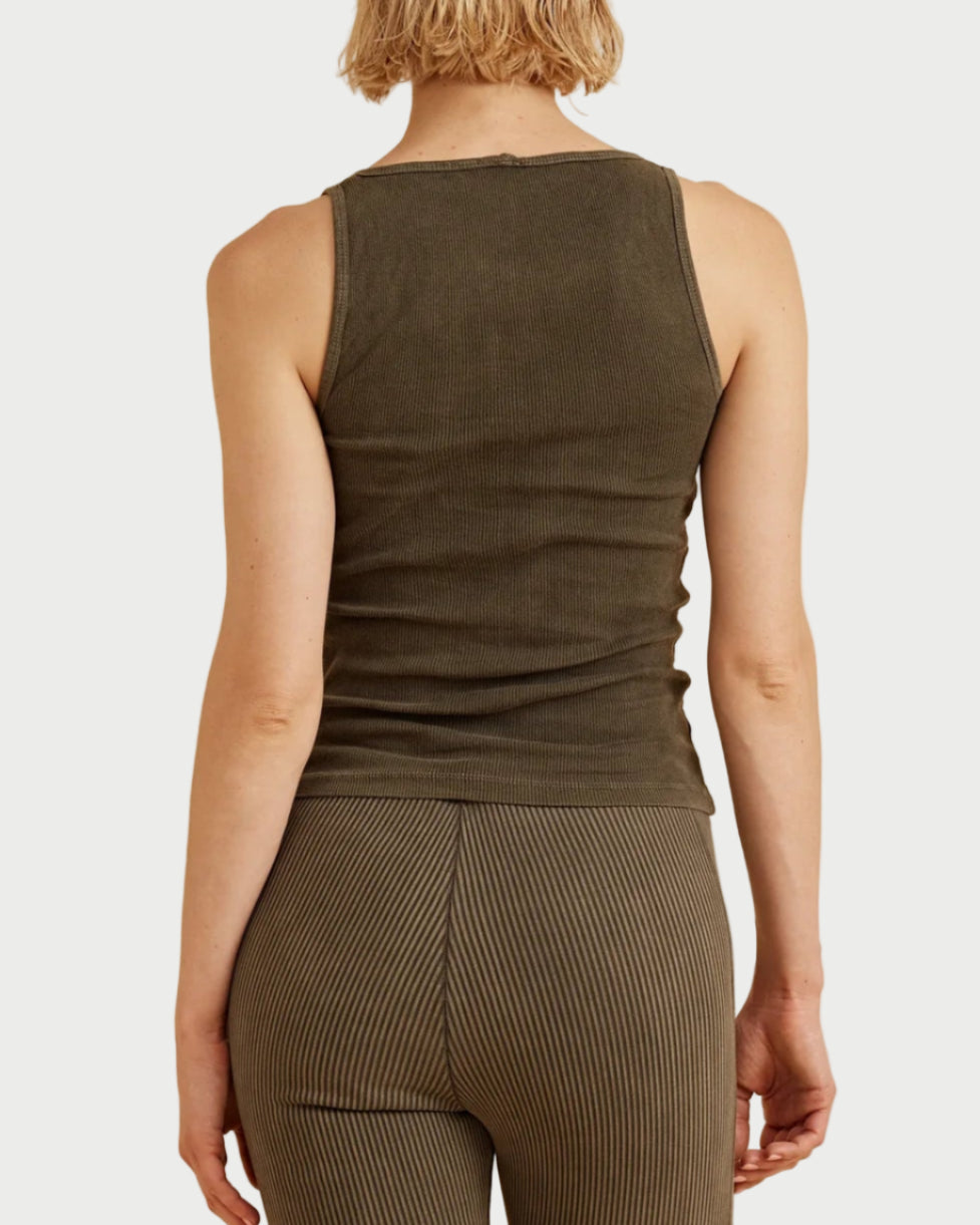 Person wearing a green sleeveless top and capri pants on a beige background