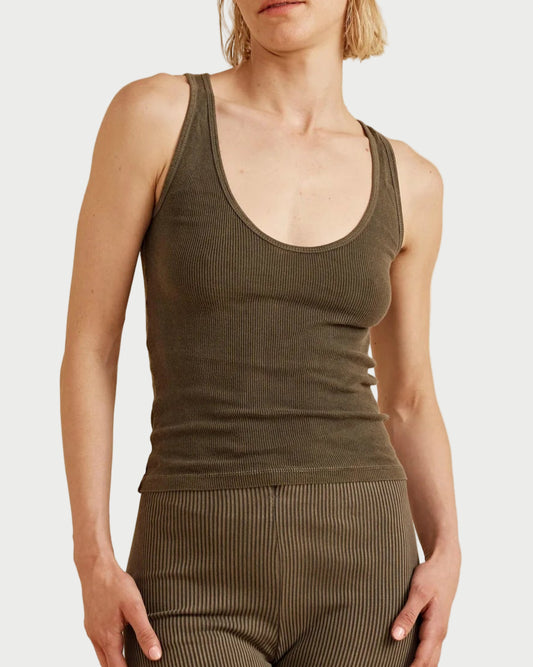 Woman wearing a green tank top and capri pants against a beige background