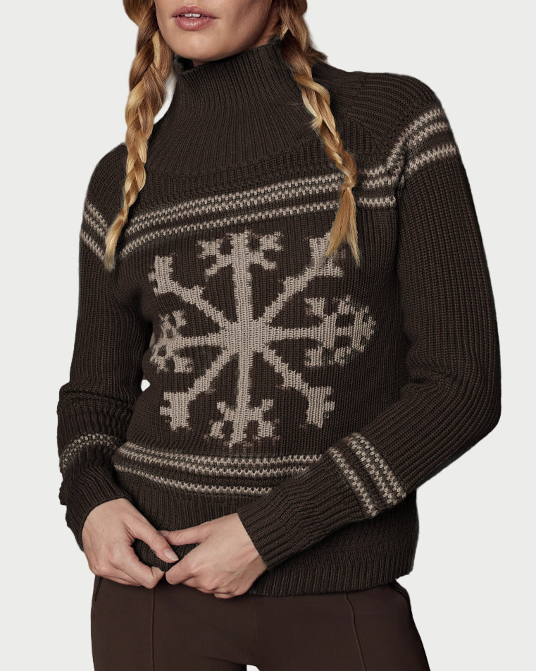 Woman wearing a brown knit sweater with a snowflake pattern and matching beanie against a textured gray background.
