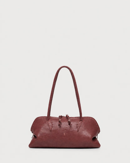 A slouchy, rounded maroon Henry Beguelin Bolla Bassa Bag with a top handle, showcasing fine Italian craftsmanship.