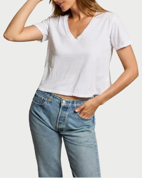 Woman wearing a white t-shirt and blue jeans against a plain background