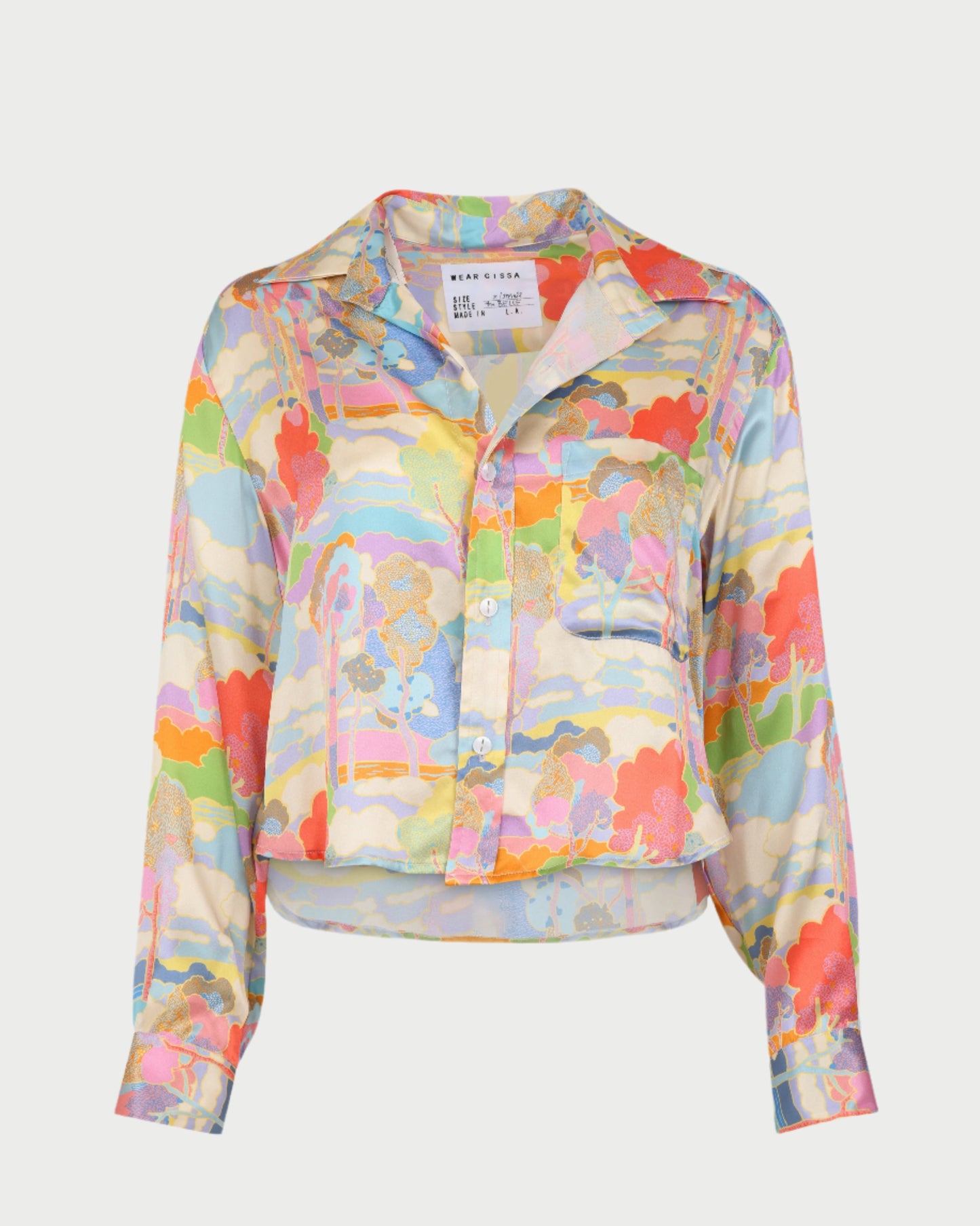 The Belle Shirt by WEAR CISSA is a long-sleeved Liberty silk button-up with an Art Nouveau print in pink, orange, blue, yellow, and green. It features a collar, front pocket, relaxed fit, and slightly cropped length.
