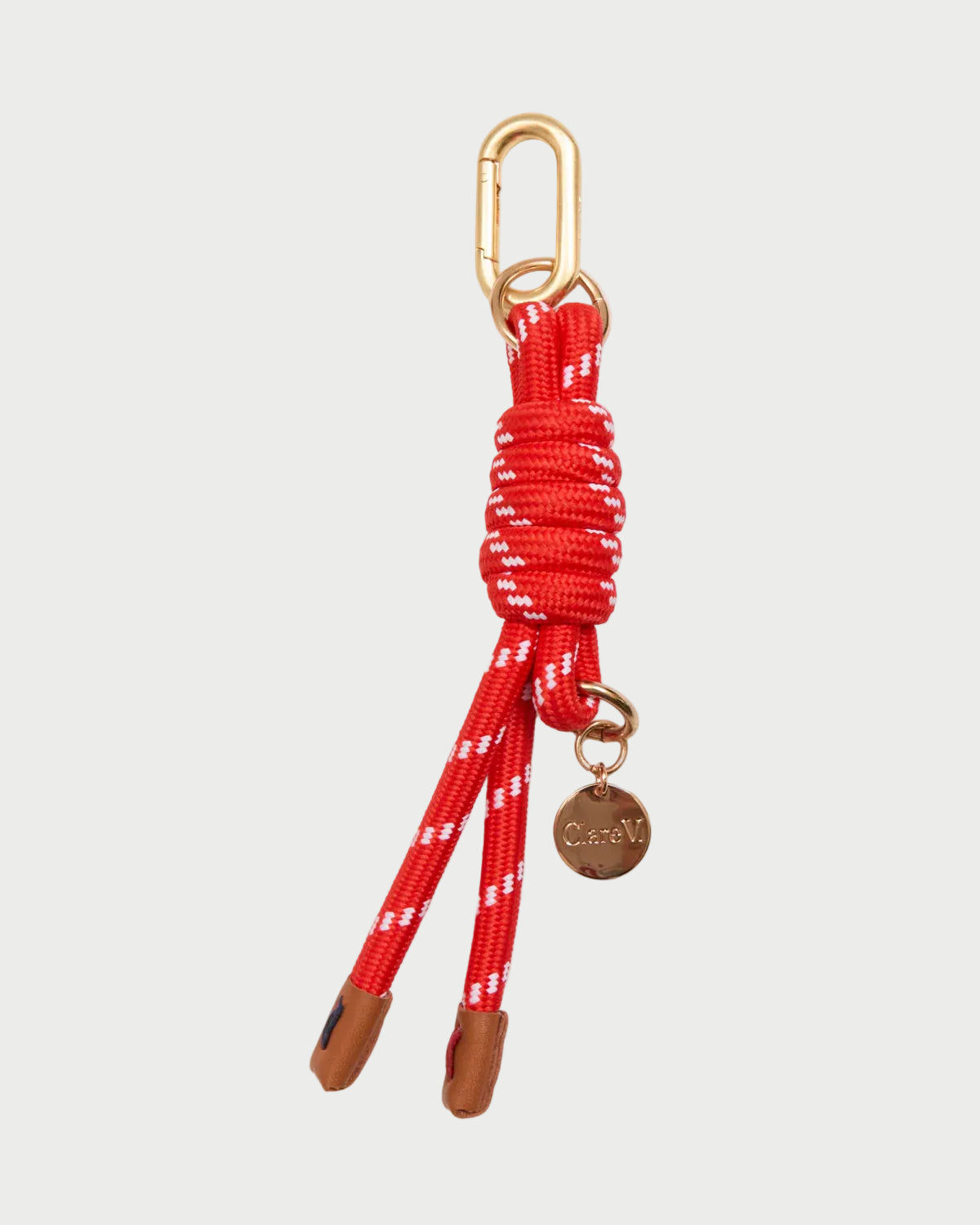 Red dog leash with gold carabiner and brown leather ends on a white background
