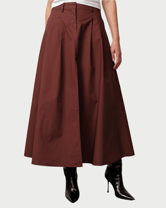 Person wearing a brown skirt and white top against a plain background