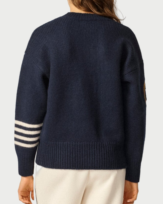Person wearing a navy sweater with white stripes and white pants on a light background