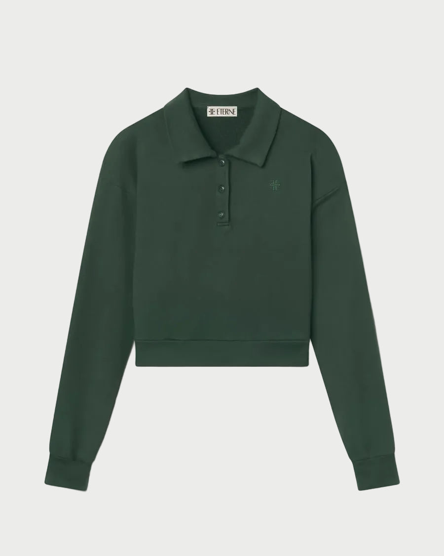 The Éterne Cropped Polo Sweatshirt by Eterne is a dark green, long-sleeve cropped sweatshirt made from soft French terry. It features a relaxed fit with a collar, button placket, and a subtle chest logo, shown against a white background.