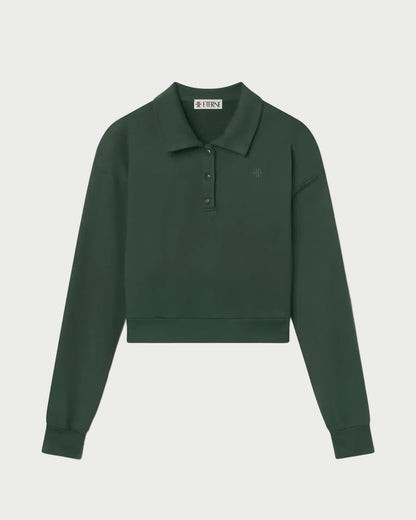 The Éterne Cropped Polo Sweatshirt by Eterne is a dark green, long-sleeve cropped sweatshirt made from soft French terry. It features a relaxed fit with a collar, button placket, and a subtle chest logo, shown against a white background.