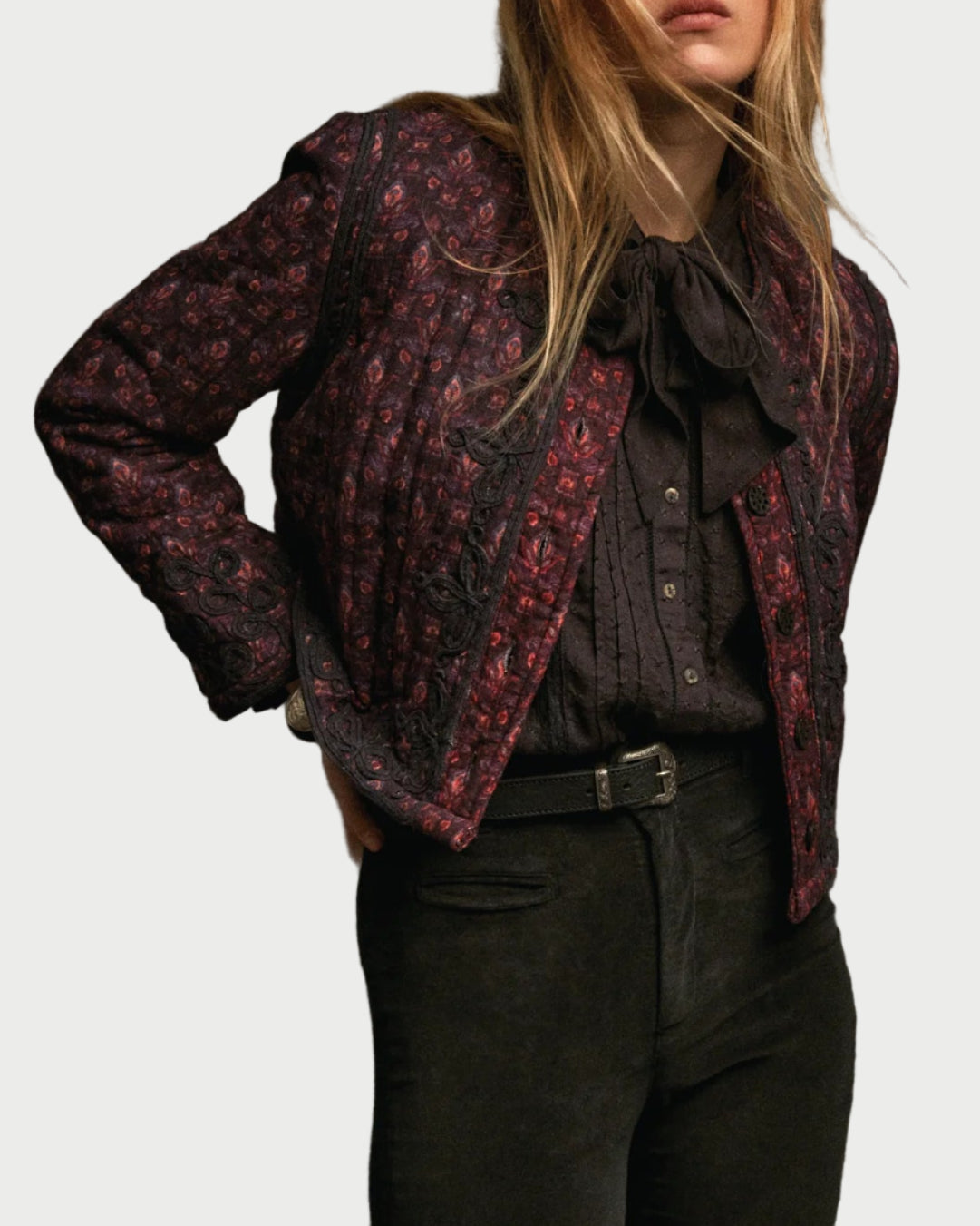 Person wearing a patterned jacket over a black shirt against a gray background