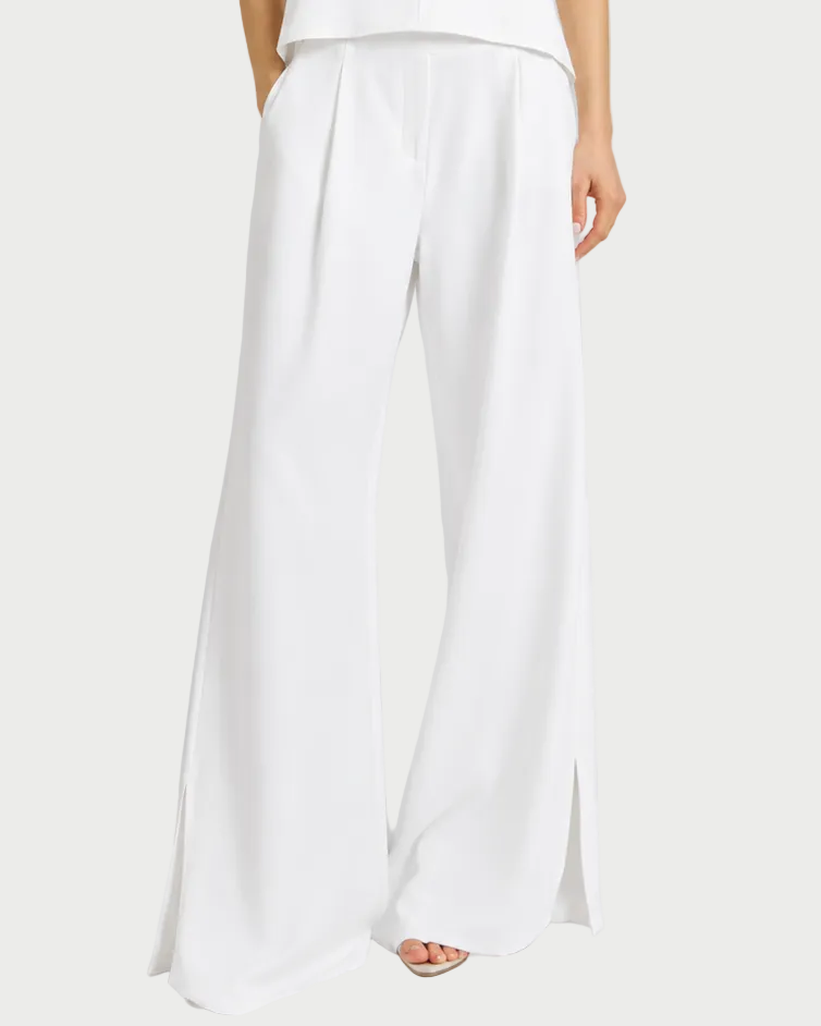 Woman wearing a white sleeveless top and wide-leg pants on a gray background