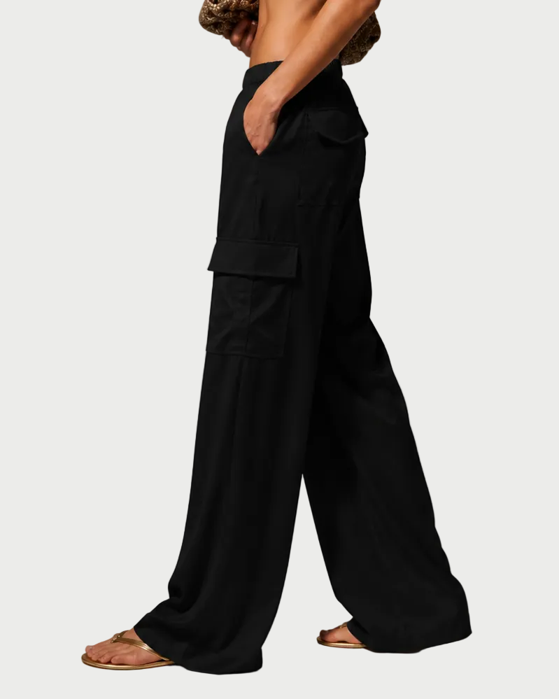 Woman wearing a white top and black pants against a gray background