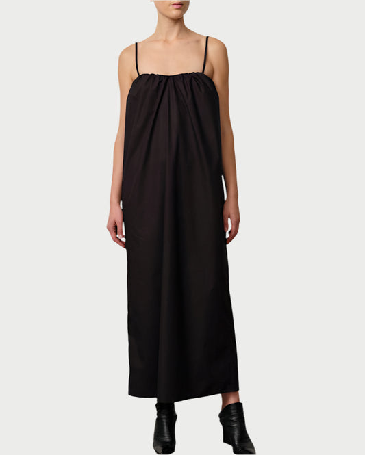 Woman wearing a black dress standing against a plain background