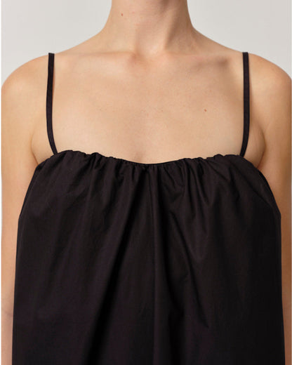 Black dress with thin straps on a neutral background
