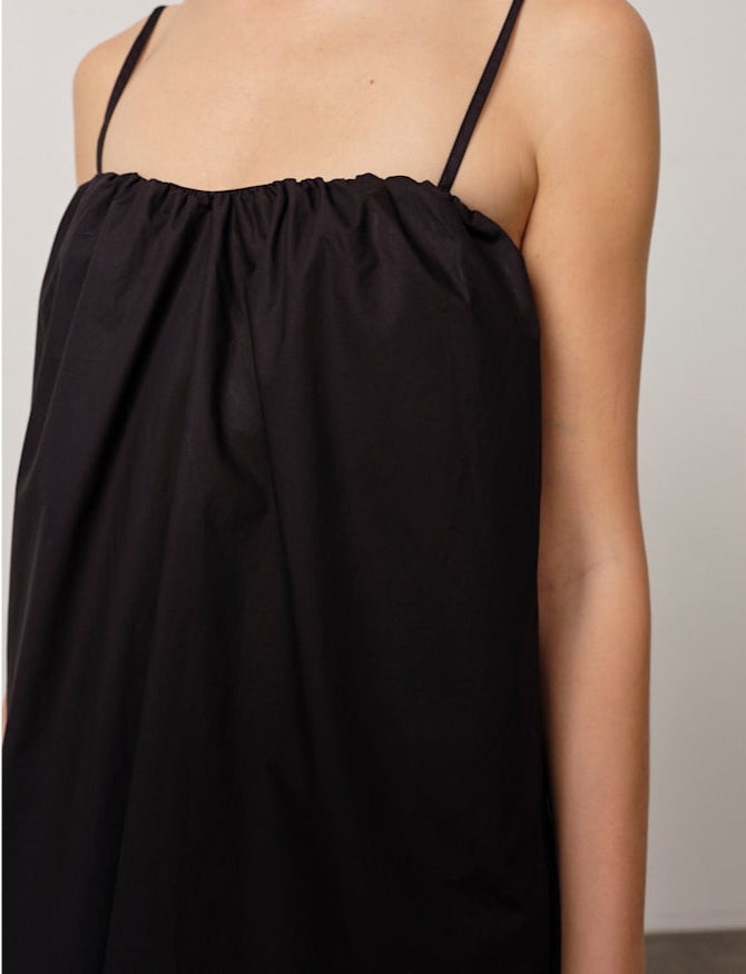 Black slip dress with thin straps on a neutral background