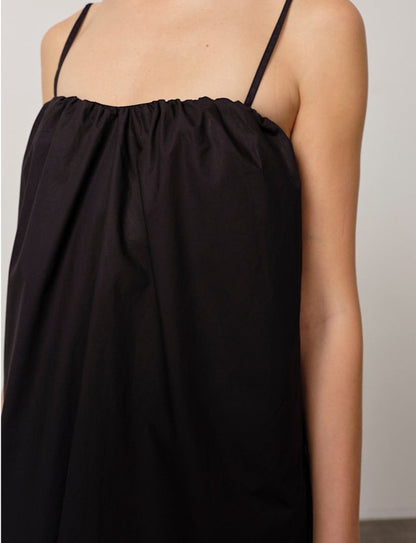 Black slip dress with thin straps on a neutral background
