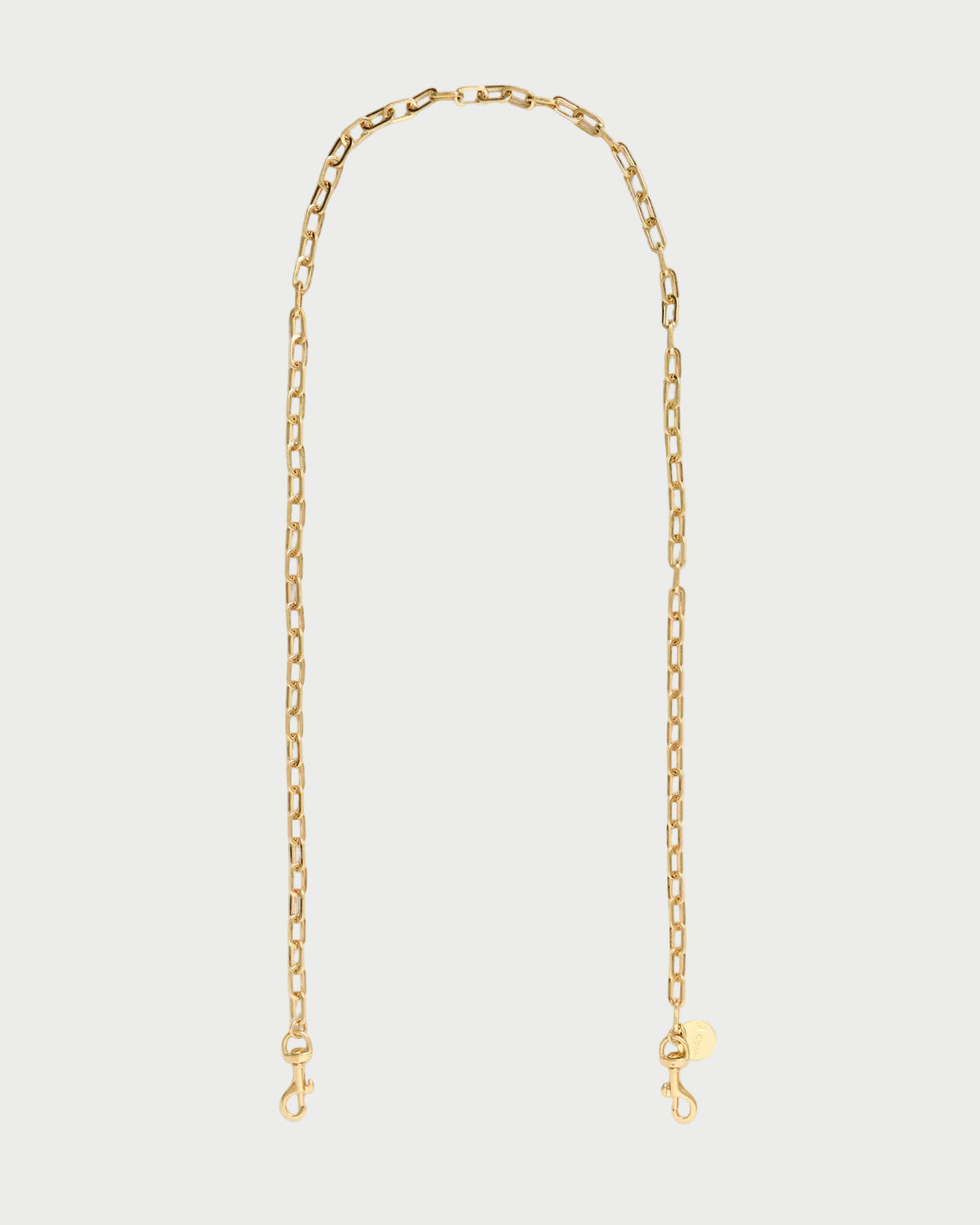 A delicate gold chain necklace with a small round tag and lobster clasp closure, displayed against a clean white background.