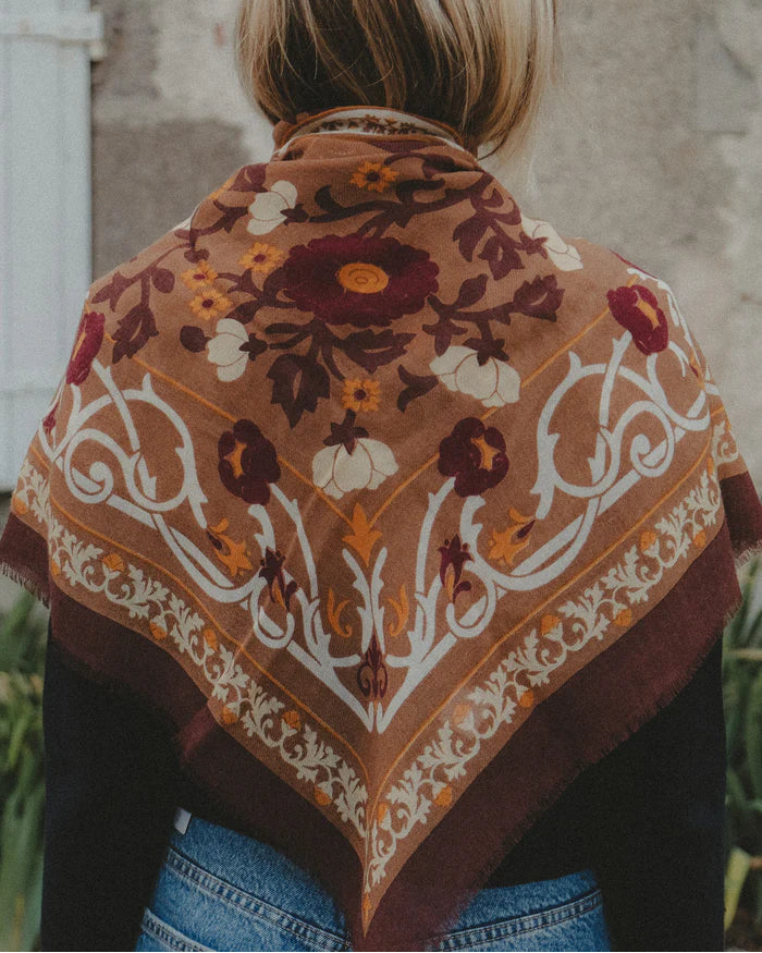Person wearing a patterned scarf with a stone wall background