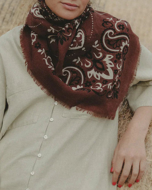 Woman wearing a patterned scarf in front of hay bales