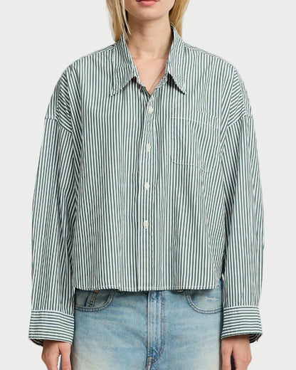 A person wears the Denimist Cropped Stripe Shirt—loose-fitting with white and green stripes, long sleeves, chest pocket—paired with light blue denim jeans. The shirt is by Denimist, and the person’s head is partially out of frame.
