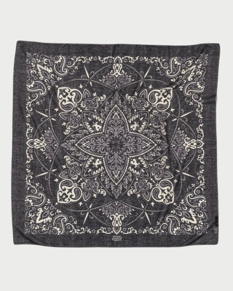 The Bandana Scarf Black by Maison Lecomte Flament is crafted from soft cotton voile and showcases an intricate white paisley and floral pattern, a bold star-shaped center motif, and elegant decorative borders.