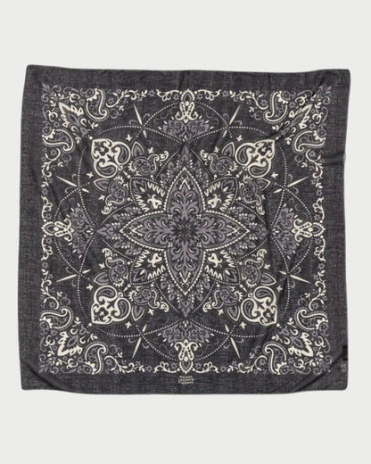 The Bandana Scarf Black by Maison Lecomte Flament is crafted from soft cotton voile and showcases an intricate white paisley and floral pattern, a bold star-shaped center motif, and elegant decorative borders.