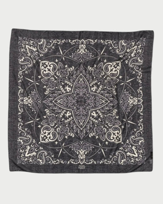 The Bandana Scarf Black by Maison Lecomte Flament is crafted from soft cotton voile and showcases an intricate white paisley and floral pattern, a bold star-shaped center motif, and elegant decorative borders.