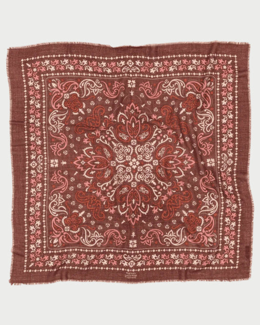 The Saint Emilion Scarf by Maison Lecomte Flament is a square, brown bandana-style accessory with an intricate paisley and floral print in red, white, and pink hues, decorative borders, and slightly frayed edges.