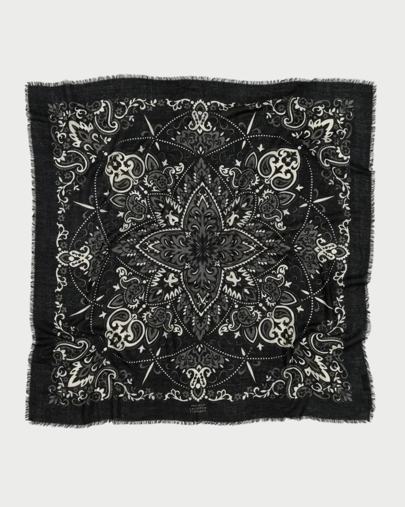 The Maison Lecomte Flament Bandana Scarf Black features intricate white paisley and floral patterns with a central star-like motif and frayed edges—a signature accessory from Maison Lecomte Flament.