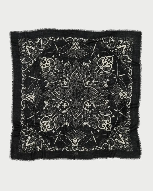 The Maison Lecomte Flament Bandana Scarf Black features intricate white paisley and floral patterns with a central star-like motif and frayed edges—a signature accessory from Maison Lecomte Flament.