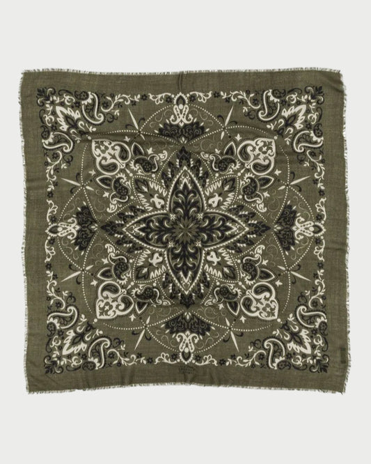 The Bandana Scarf Khaki by Maison Lecomte Flament is a square cotton voile bandana with a fringed edge, featuring a symmetrical paisley and floral design in black, white, and olive green.