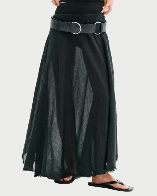A person wearing the All III Elysia Maxi Skirt by All III, styled with a wide black belt and black flip-flops, stands against a plain background, with only the lower half of their body visible.