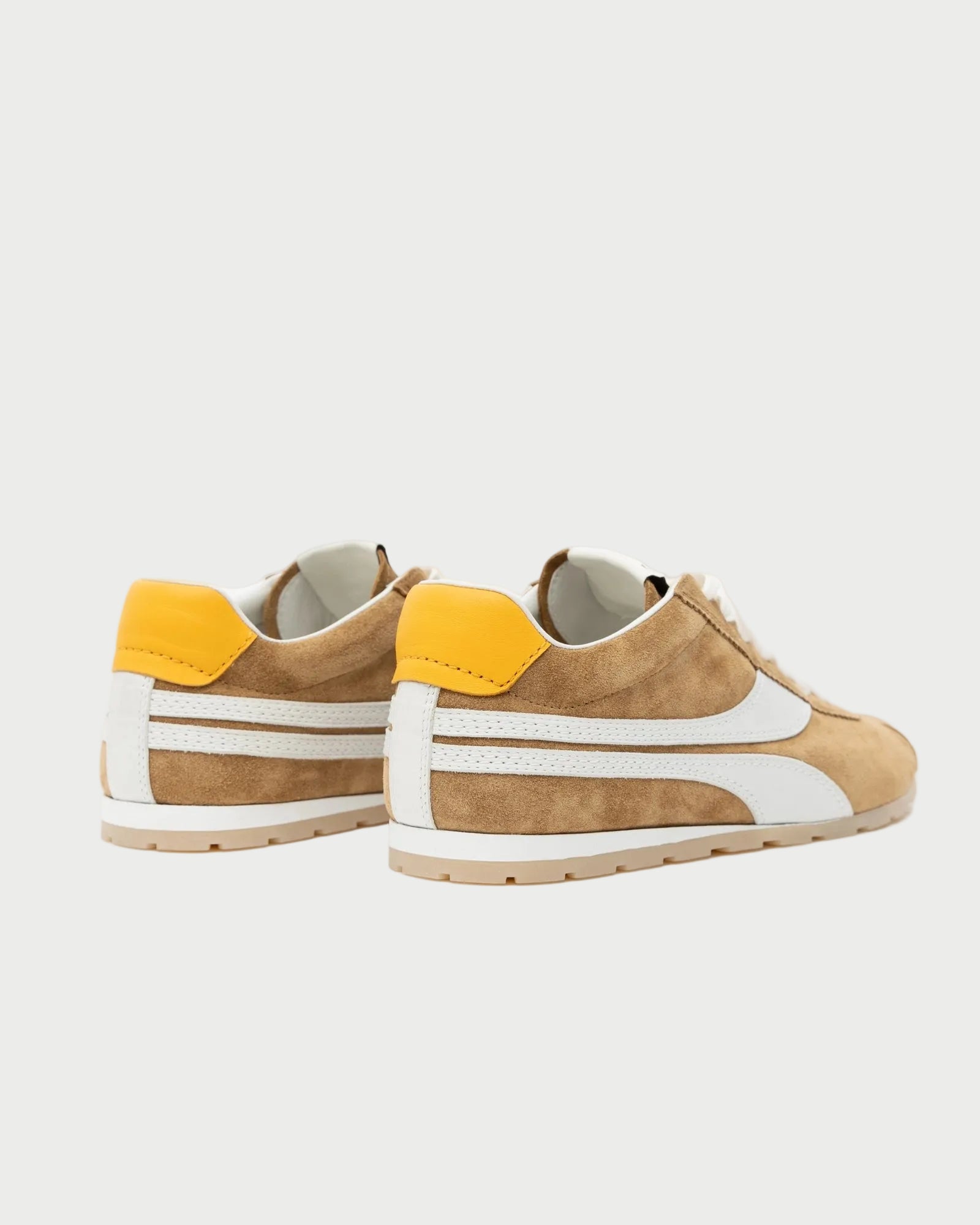 The Oncept Essex Sneaker - Ginger is a brown suede sneaker with white accents and yellow heel tabs, shown on a white background at an angle to highlight the back and side. These eco-conscious sneakers blend style and comfort from Oncept.