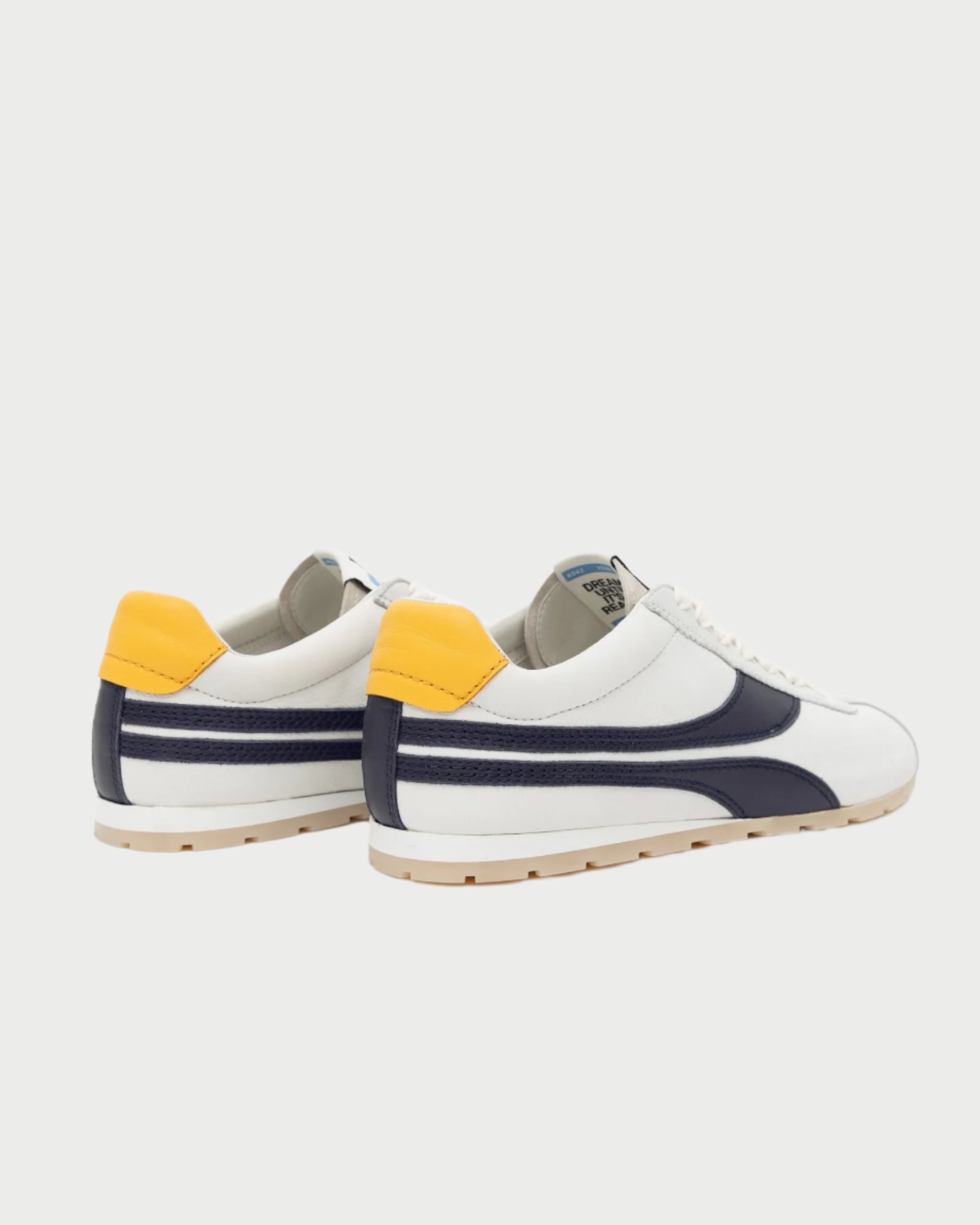 The Essex Sneakers by Oncept are white with dark blue stripes and yellow heel accents. Featuring a vintage design, they include a white sole and lace-up closure, perfectly combining classic style with modern flair against a light background.