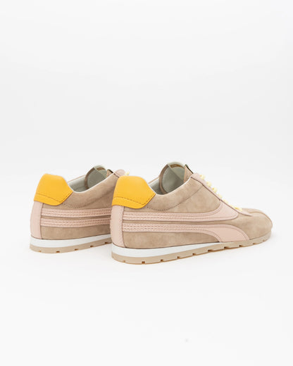 Beige sneakers with yellow accents on a white background