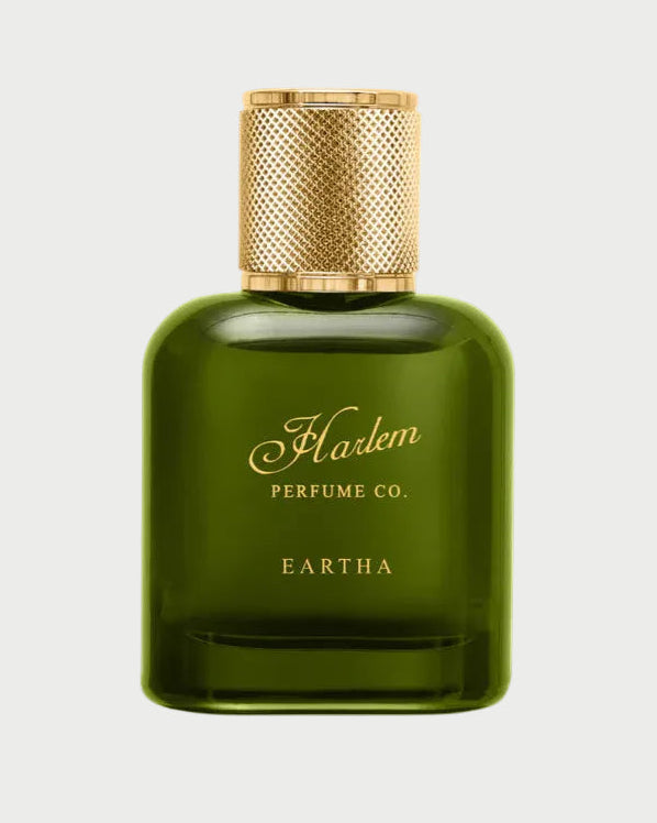 A green glass bottle of EARTHA EAU DE PARFUM by Harlem Perfume Co., featuring a gold textured cap and label with gold script, embodies fearless sophistication—shown against a white background.
