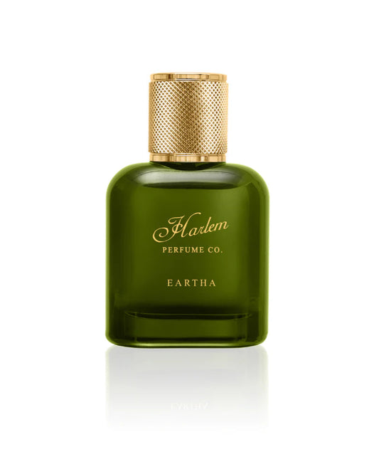 A green glass bottle of EARTHA EAU DE PARFUM by Harlem Perfume Co., featuring a gold textured cap and label with gold script, embodies fearless sophistication—shown against a white background.